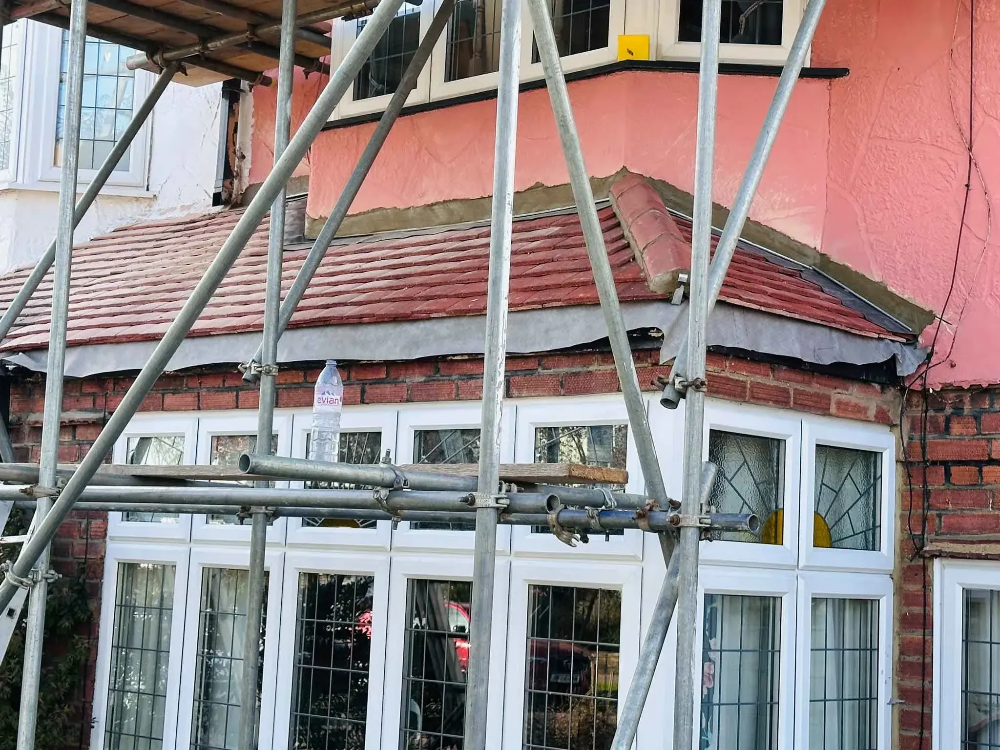 Tiled roof covering above a bay window on a house in Bracknell, Berkshire, seen through scaffolding