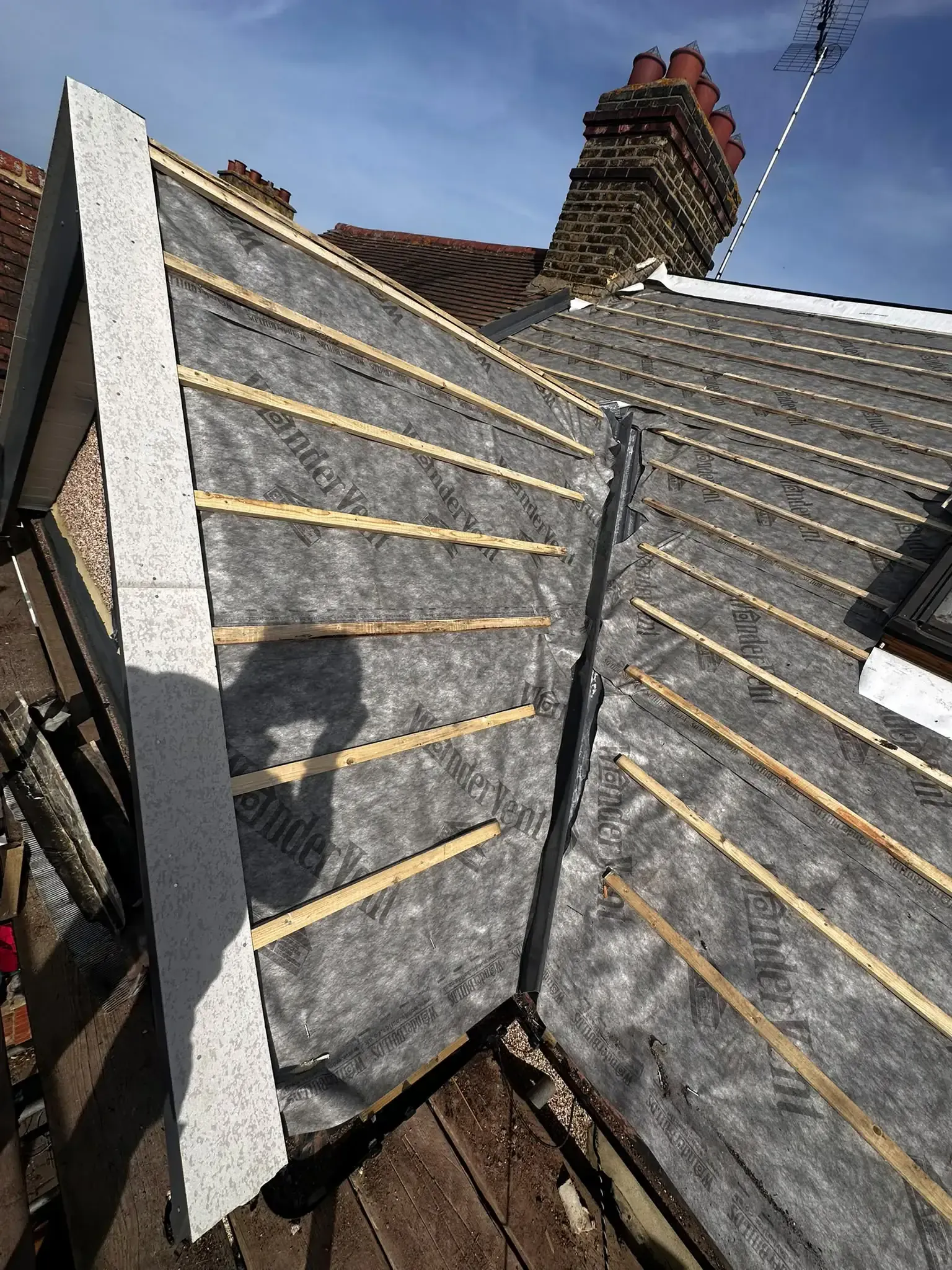 Membrane and battens meeting at a sloping roof valley during re-roofing work in Cobham