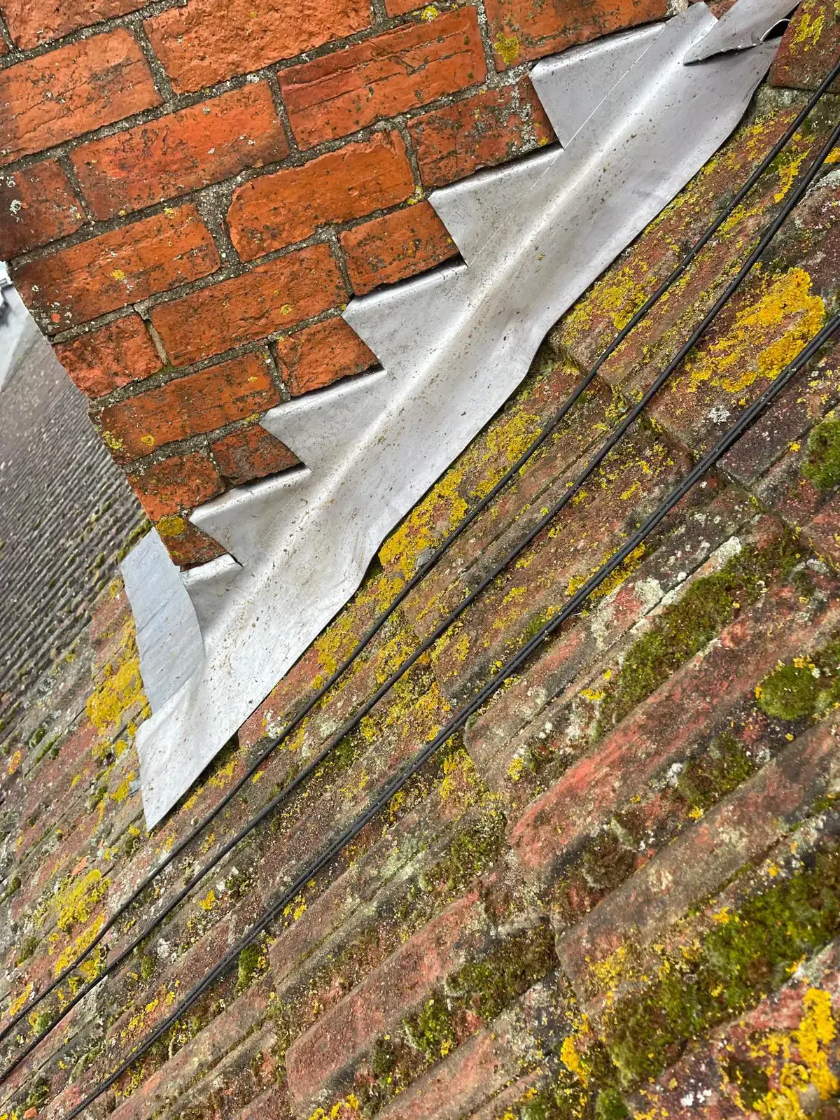 Existing flashing condition at a brick chimney and tiled roof junction in Epsom