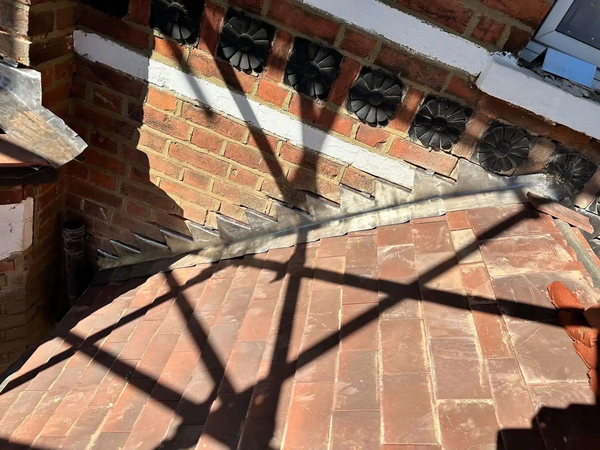 Lead step flashing at a pitched porch roof and brick wall junction in West Drayton